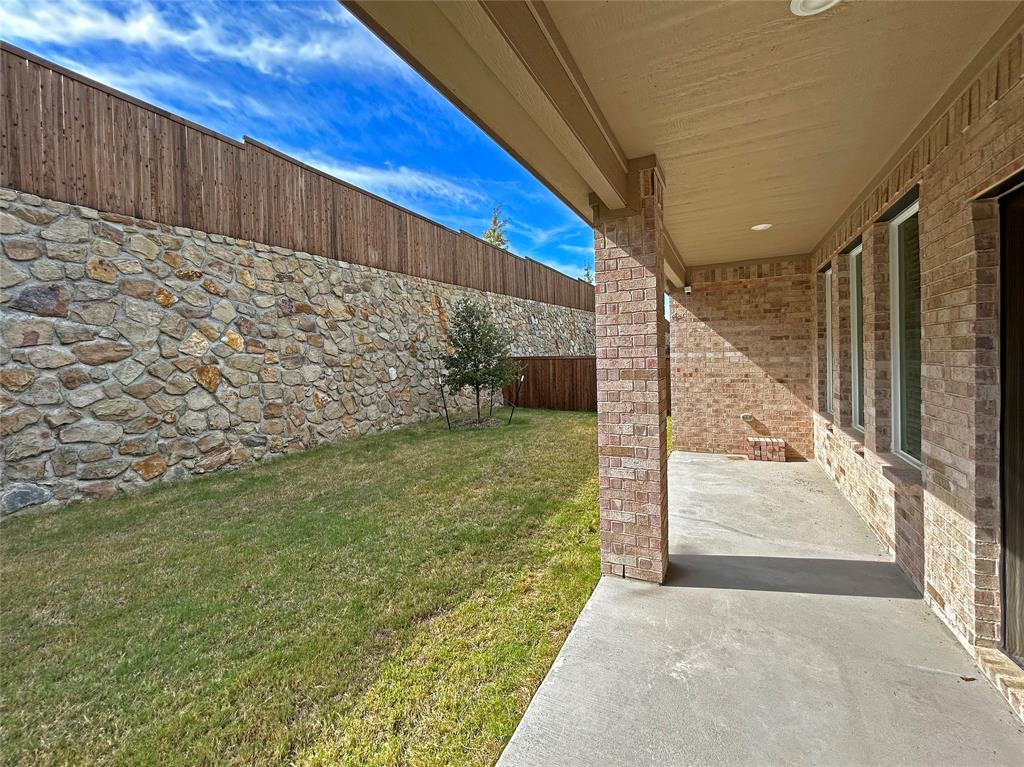 Covered concrete patio featuring recessed lighting, brick exterior walls, and an exterior stone masonry privacy wall