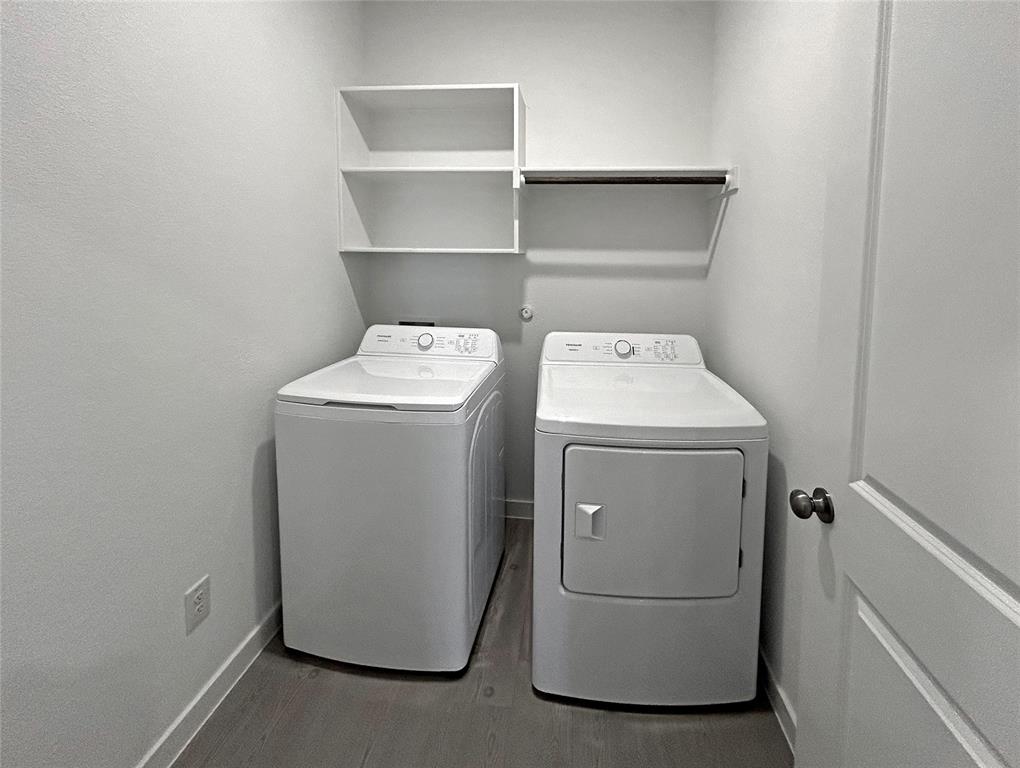 Laundry room features luxury vinyl plank flooring, built-in shelving, and a wall-mounted hanging rod