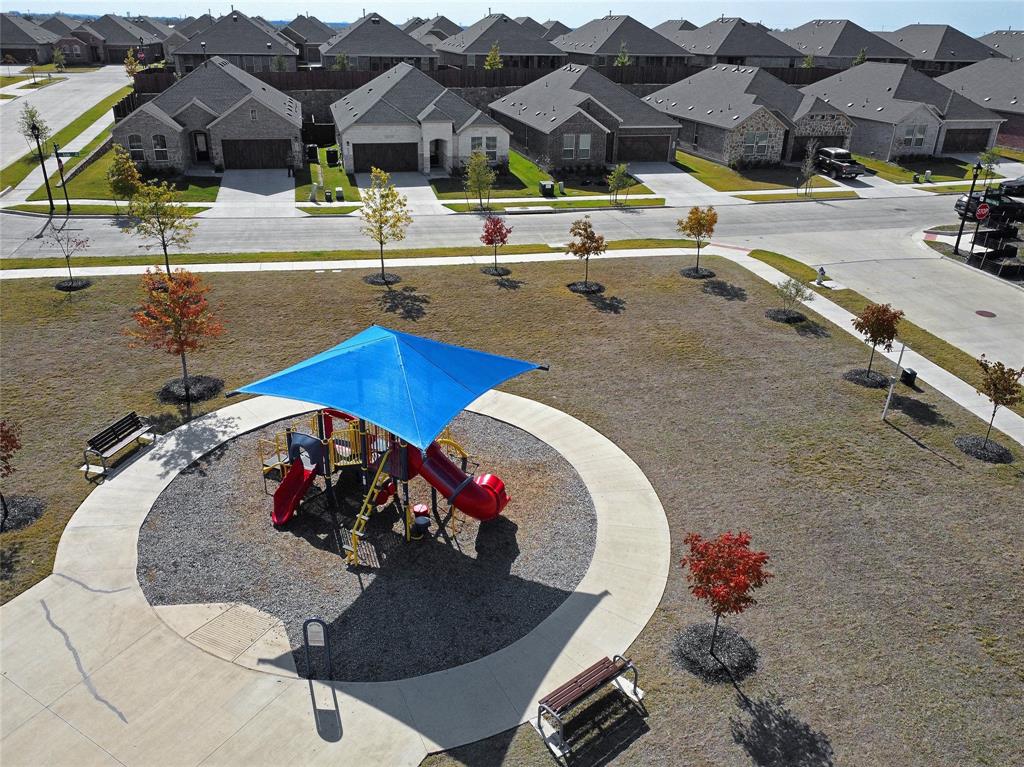 The house overlooks  a community park, which features a playground structure with a blue shade canopy, circular concrete walkway, and dedicated outdoor benches