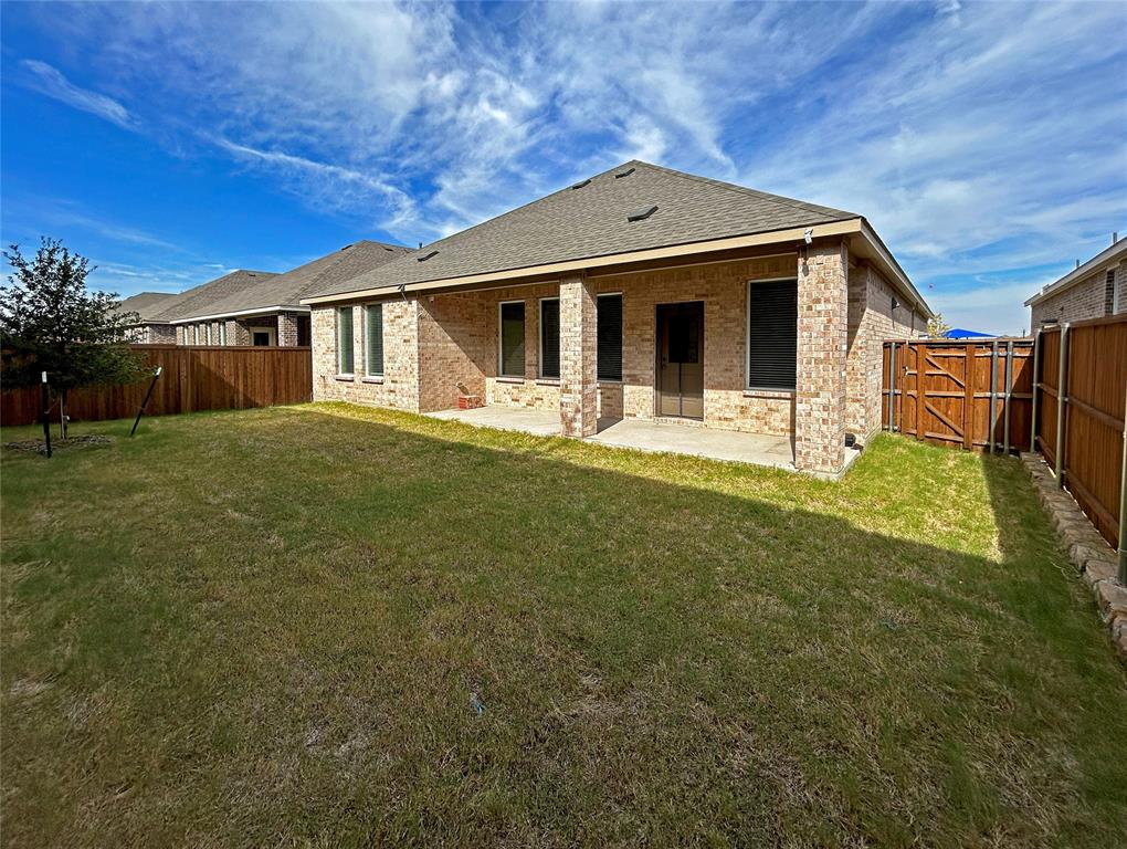 Backyard featuring a masonry exterior, a covered concrete patio, and a wood privacy fence