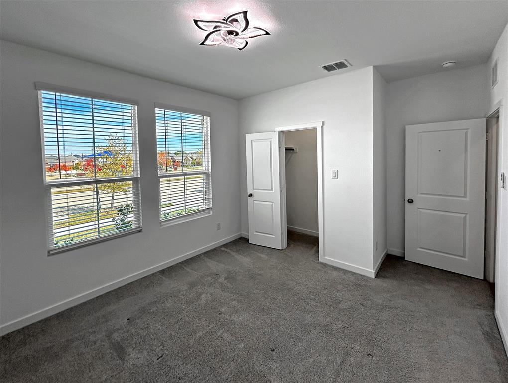 Front bedroom features two windows with horizontal blinds that overlook the neighborhood park, a walk-in closet, and a decorative ceiling light fixture