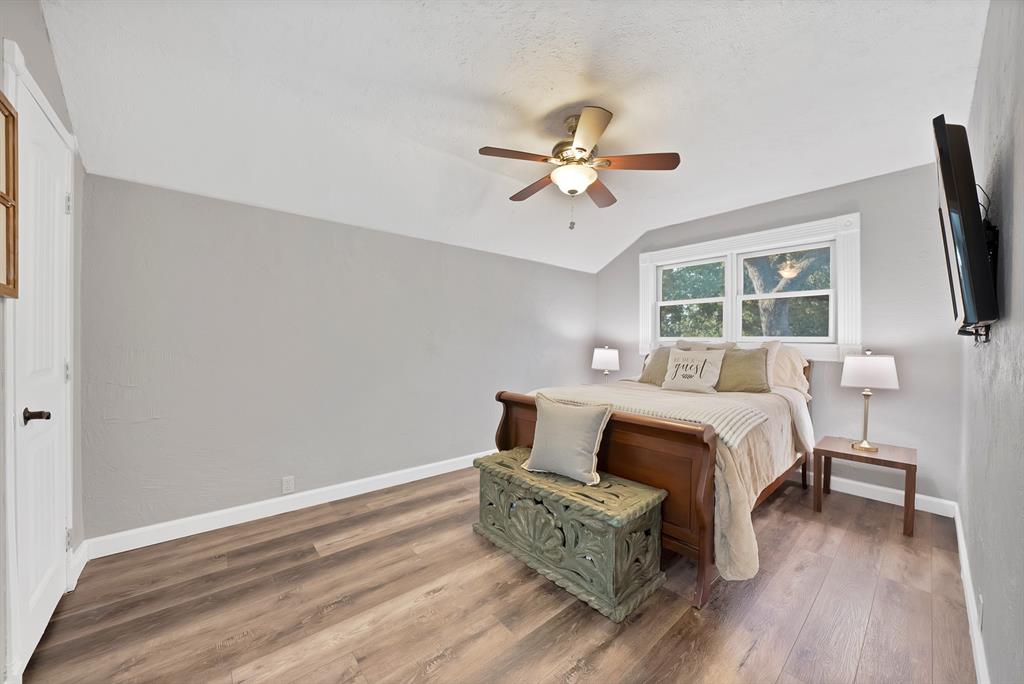 Room featuring wood-finish flooring, a vaulted ceiling, a ceiling fan with integrated lighting, and dual-pane windows