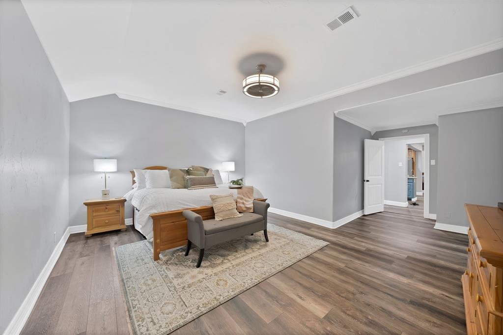 Wood-finish flooring, vaulted ceilings with crown molding, and a contemporary drum-style ceiling light fixture