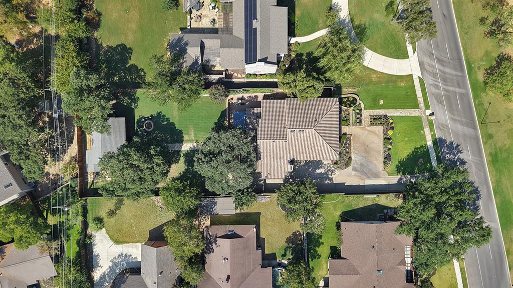 Aerial perspective featuring a lot with a paved driveway, a structured backyard with a pool, a detached storage building, and perimeter fencing