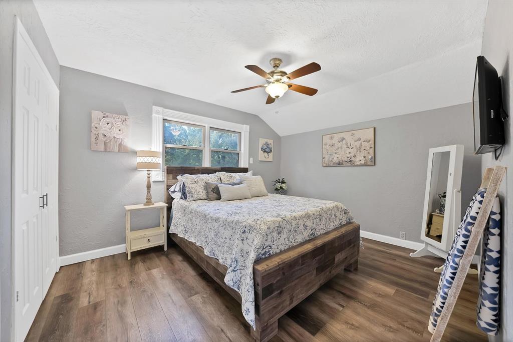 Bedroom featuring wood-finish flooring, vaulted ceiling, double-door closet, and a multi-blade ceiling fan with integrated lighting