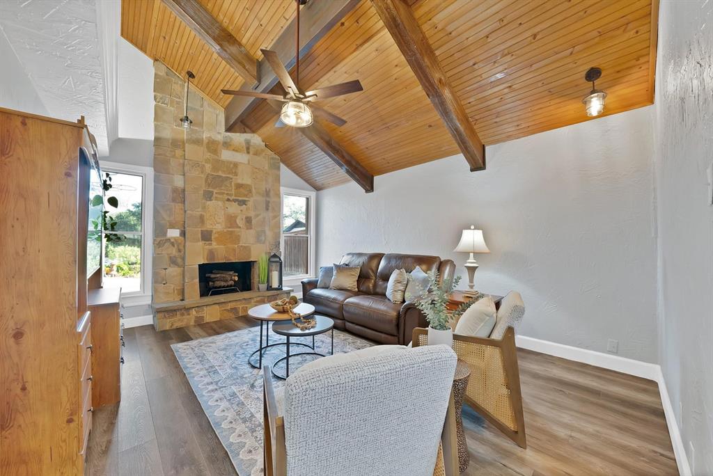 Vaulted ceiling with natural wood planking and exposed beams, full-height stone masonry fireplace, and wood-finish flooring
