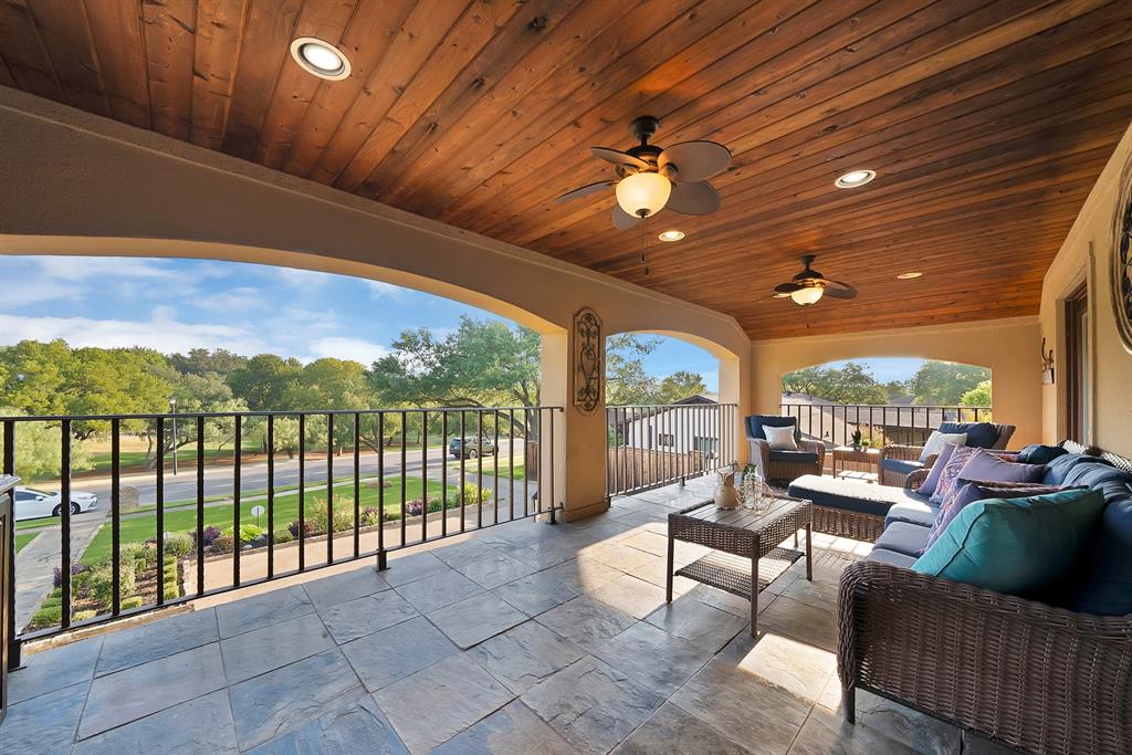 Covered balcony featuring a wood-plank ceiling, recessed lighting, ceiling fans, stone-finish tile flooring, and wrought iron railings