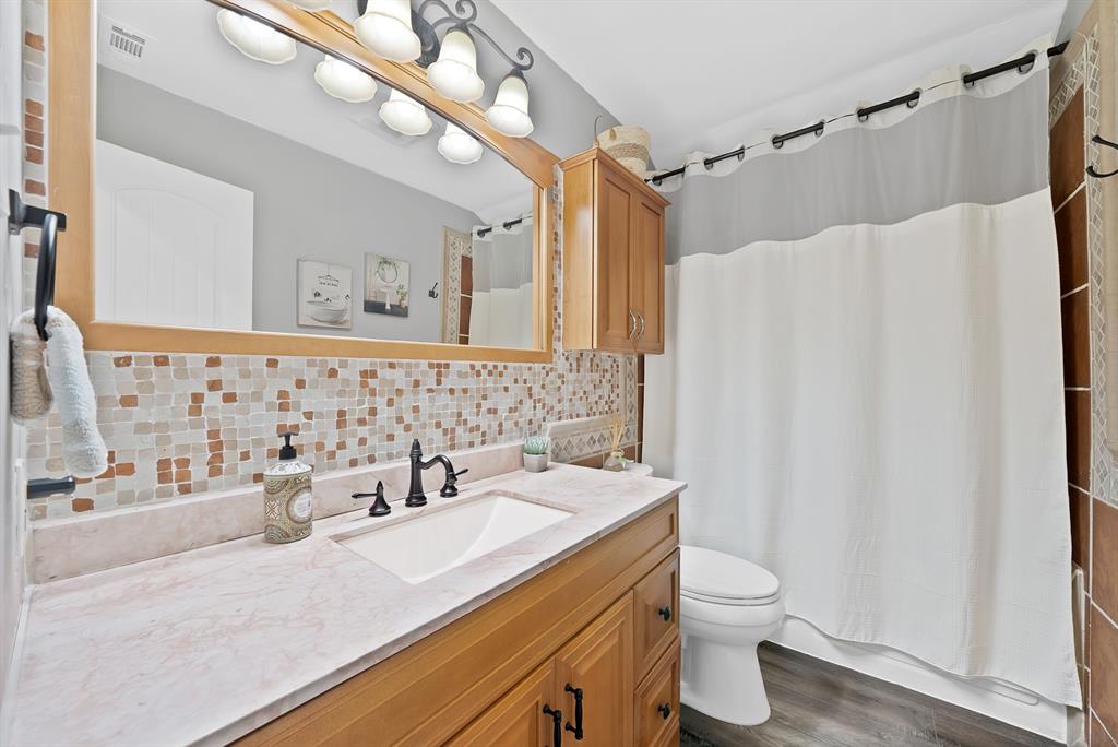 Bathroom vanity featuring a wood-tone cabinet, integrated sink, and light-toned solid surface countertop