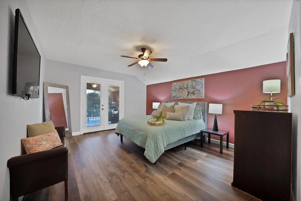 Wood-finish flooring, accent wall, ceiling fan with integrated lighting, and double glass-paned doors