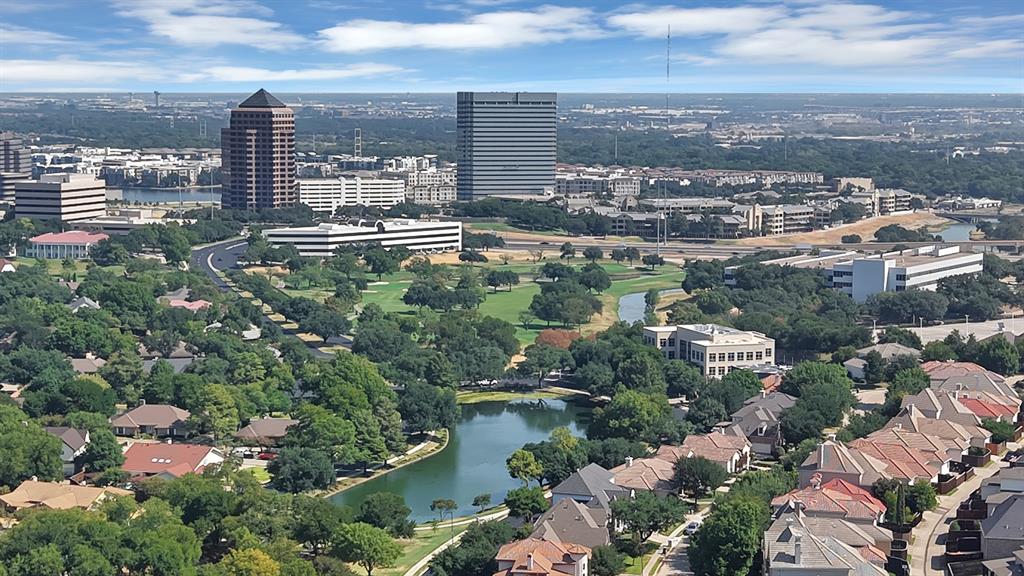 Aerial perspective showcasing extensive green space, a central water feature, and high-rise metropolitan surroundings