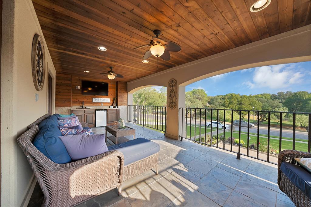 Covered balcony featuring a wood-plank ceiling, built-in wet bar, recessed lighting, ceiling fans, and black metal railings