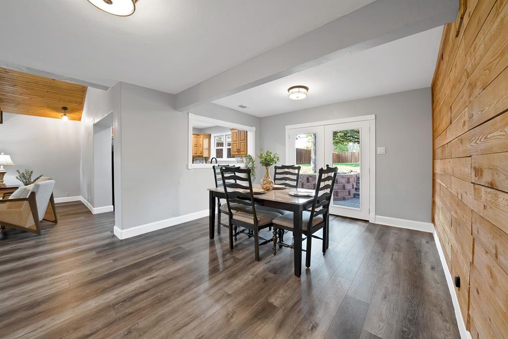 Interior space featuring wood-finish flooring, a horizontal wood-plank accent wall, dual glass-paneled exterior doors, and a service window opening
