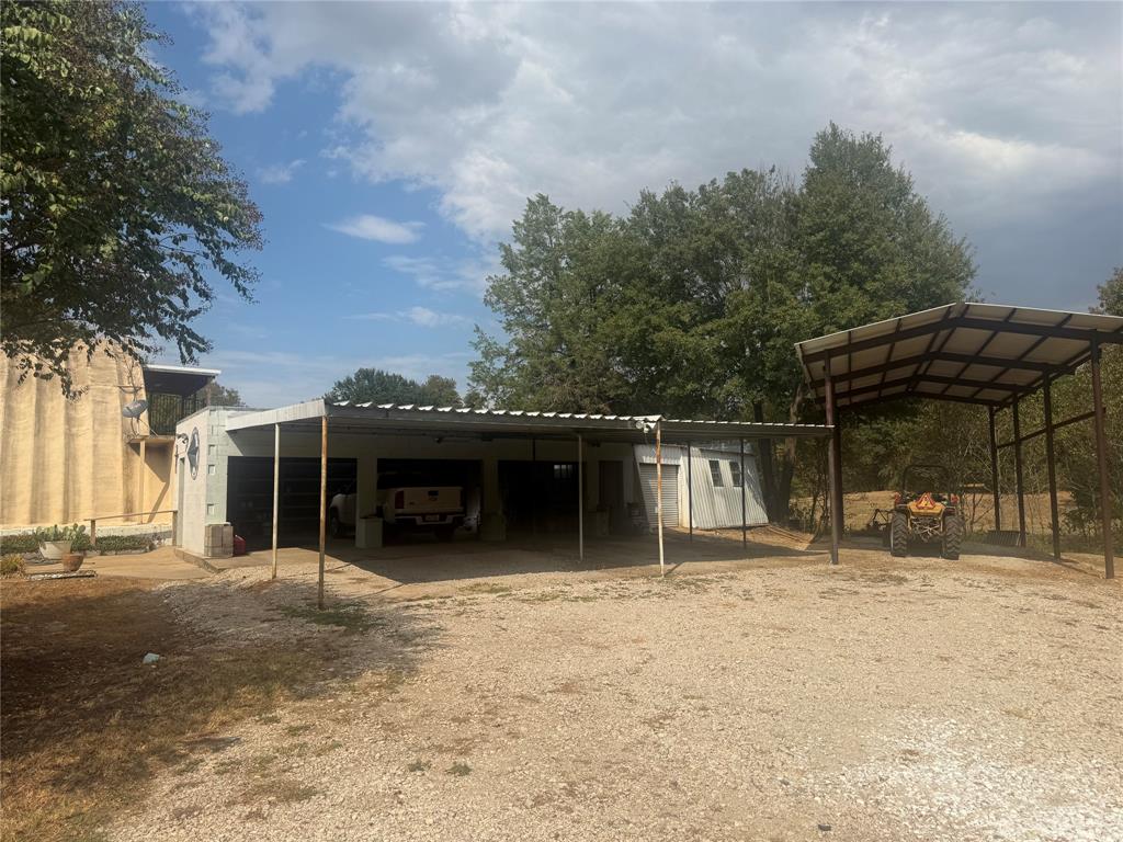 Multi-bay carport with metal roof and detached open-air storage structure