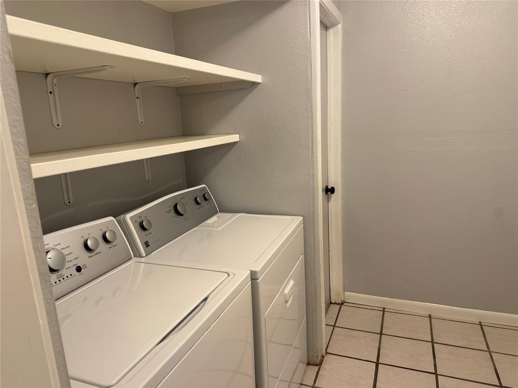 Utility room featuring ceramic tile flooring, neutral wall paint, and built-in wall-mounted shelving