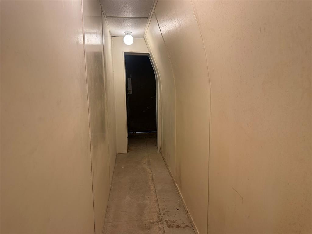 Arched hallway featuring smooth-finish walls and a globe-style flush-mount ceiling light fixture