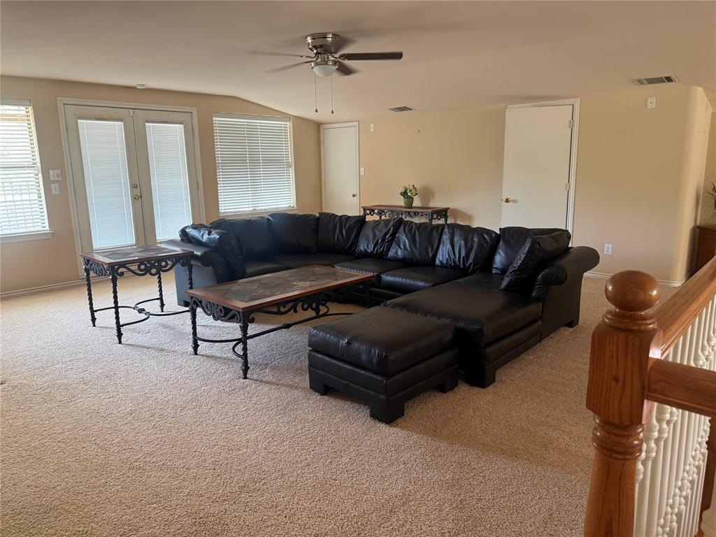 Neutral-toned room featuring high-pile wall-to-wall carpeting, ceiling fan with light fixture, glass-paneled double doors, second living space or bedroom 3