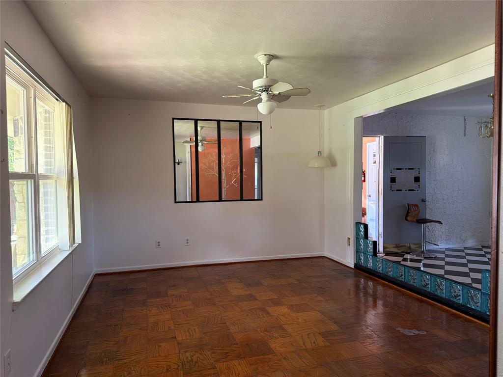 Parquet wood-finish flooring, interior multi-pane window feature, ceiling fan with integrated light fixture, pendant lighting, and decorative tiled divider wall