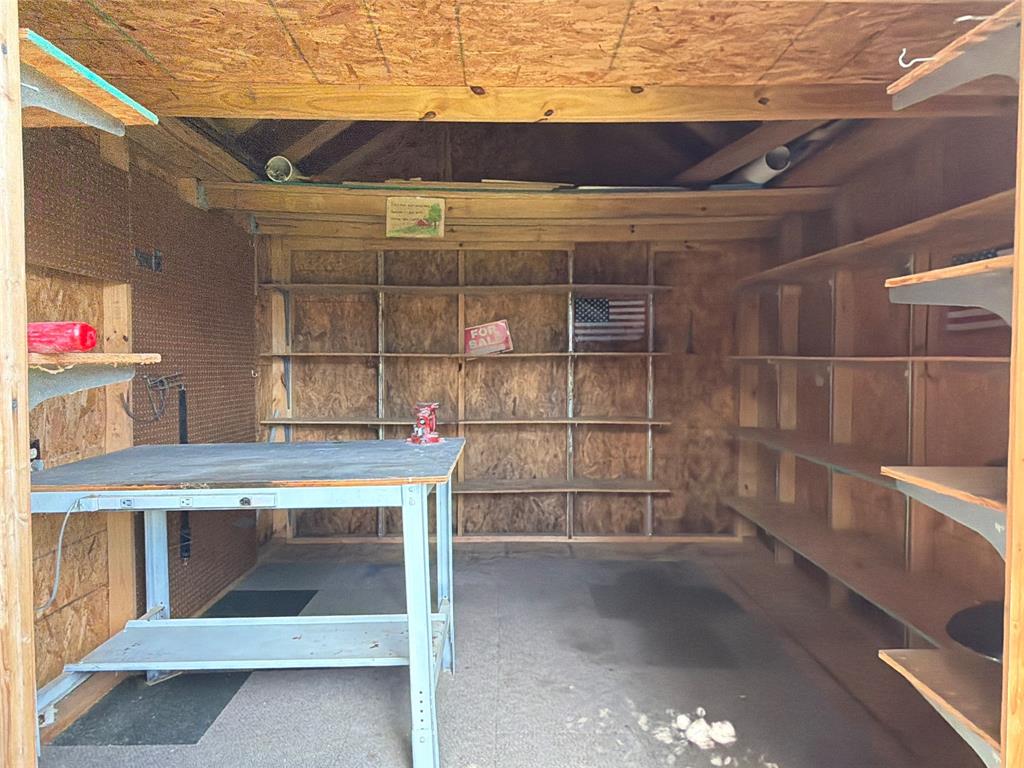 Storage structure featuring extensive built-in wooden shelving, a metal-framed workbench, and exposed timber-frame construction