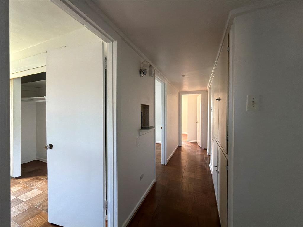 Hallway featuring parquet wood-finish flooring, built-in floor-to-ceiling storage cabinetry, and a recessed wall niche