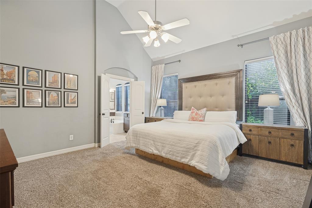 Vaulted ceiling featuring a central brushed-nickel ceiling fan with integrated light fixture, neutral wall palette, and dual-entry doors