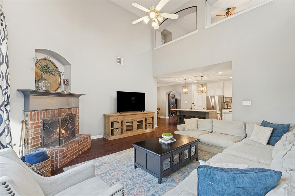 Living area featuring soaring vaulted ceilings, a full-height brick fireplace with a decorative arched niche, and dark wood-finish flooring