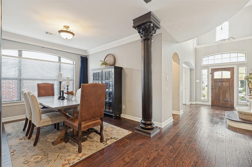Dark wood-finish flooring, decorative Corinthian-style column, arched doorways, arched window transoms, and wood-paneled front door