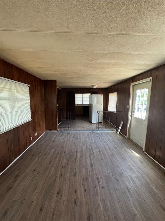 Interior space featuring wood-finish flooring, wood-paneled walls, a textured ceiling, and a multi-pane exterior entry door