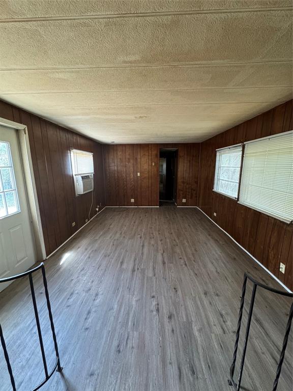 Interior space featuring wood-finish paneling, wood-finish flooring, multi-pane glass entry door, and large windows with horizontal blinds
