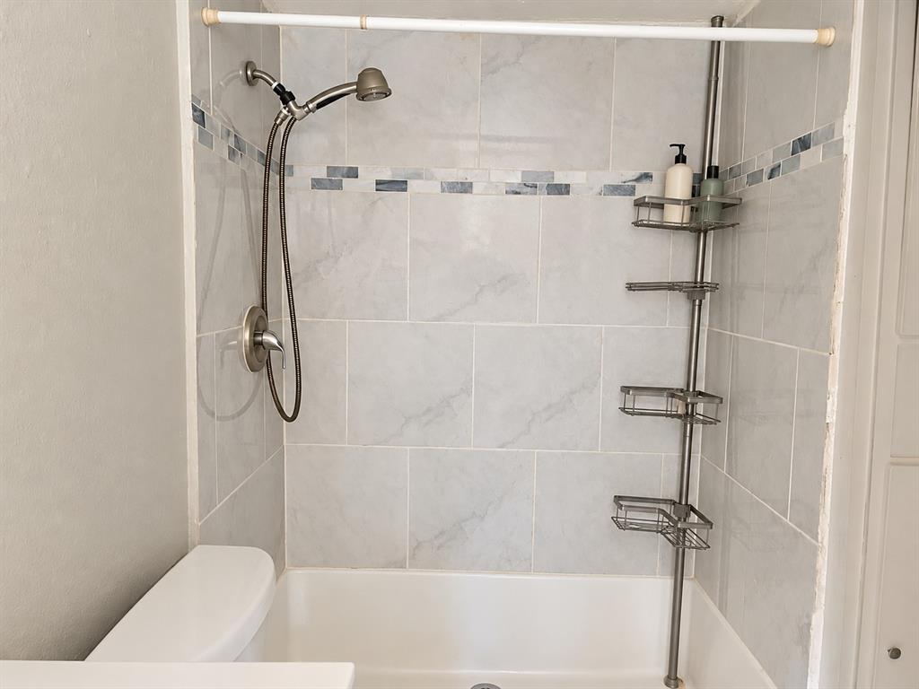 Shower featuring full-height tile surround, horizontal mosaic decorative inlay, and brushed-nickel handheld shower fixture