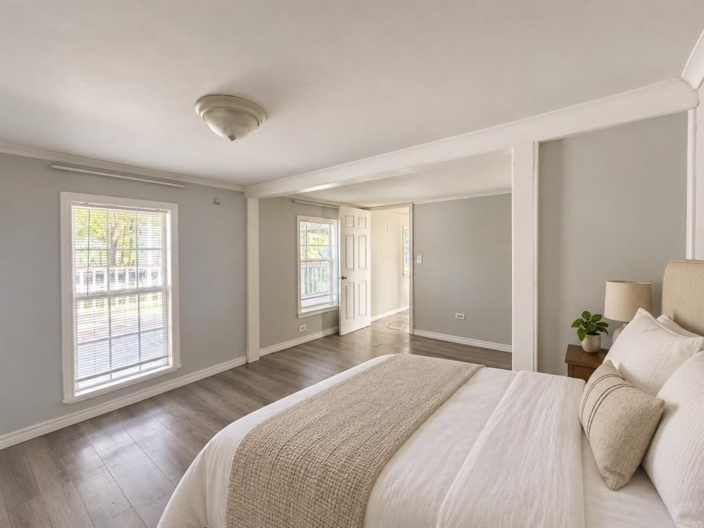 Neutral-toned interior featuring wood-finish flooring, multi-pane windows, crown molding, and a dome ceiling light fixture