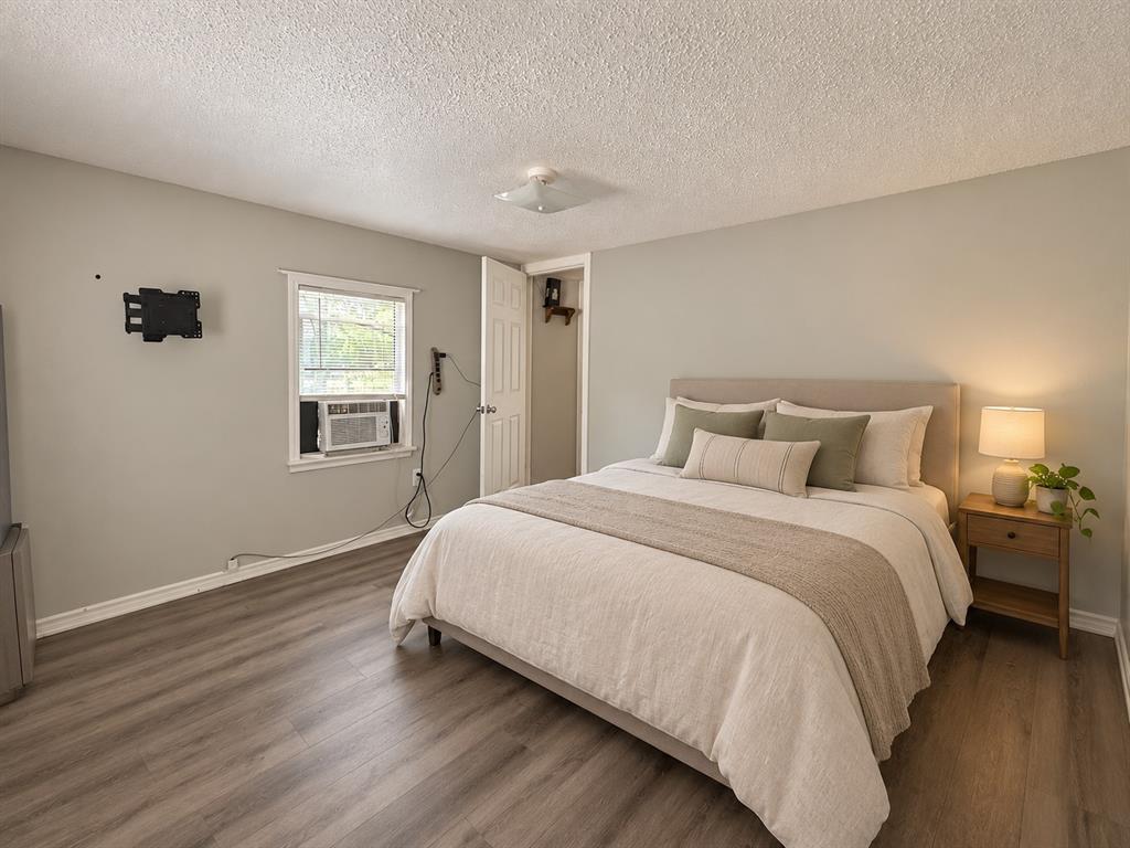 Neutral-toned bedroom featuring wood-finish flooring, a single-hung window, and a flush-mount ceiling light fixture