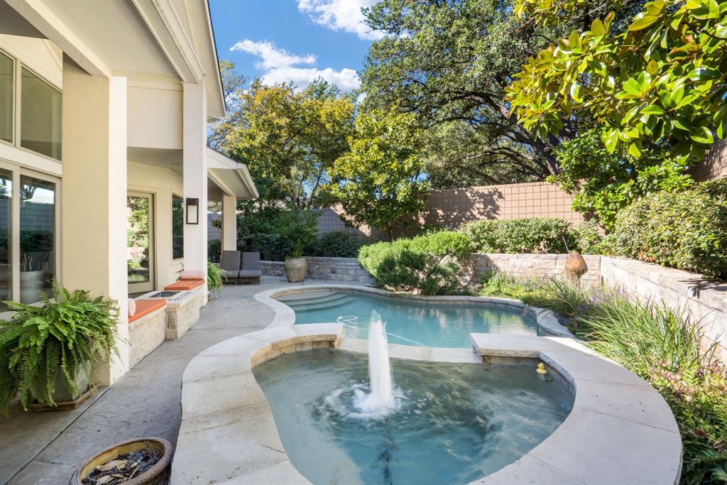 Covered patio featuring stone masonry, an integrated pool and spa combination, stone coping, and a central water fountain