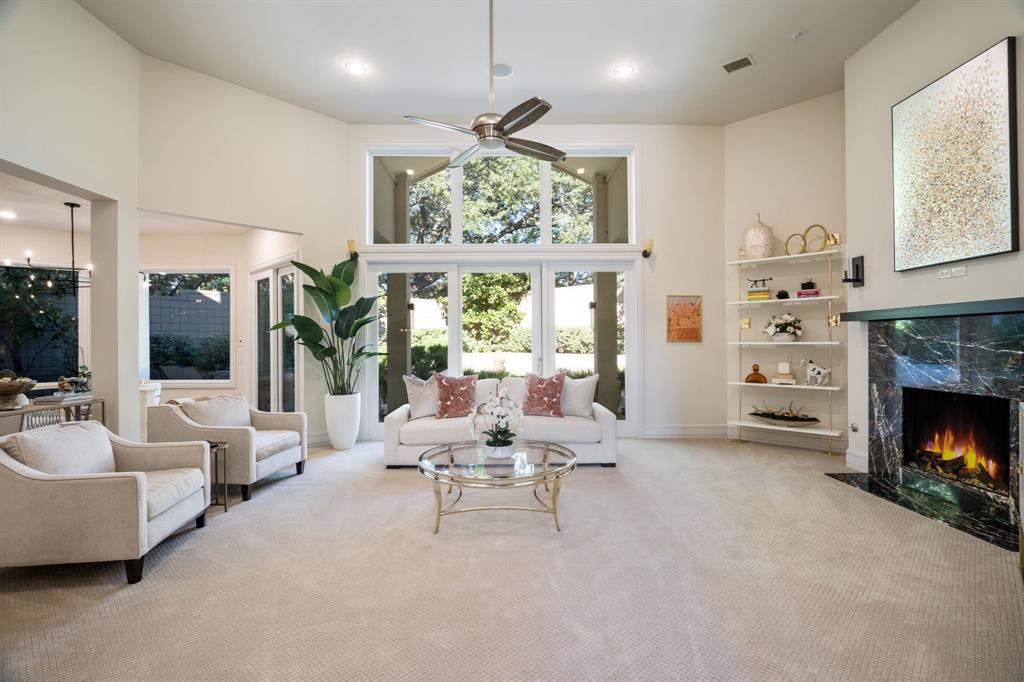 High ceilings with recessed lighting, floor-to-ceiling window wall, fireplace with dark stone surround, and built-in shelving