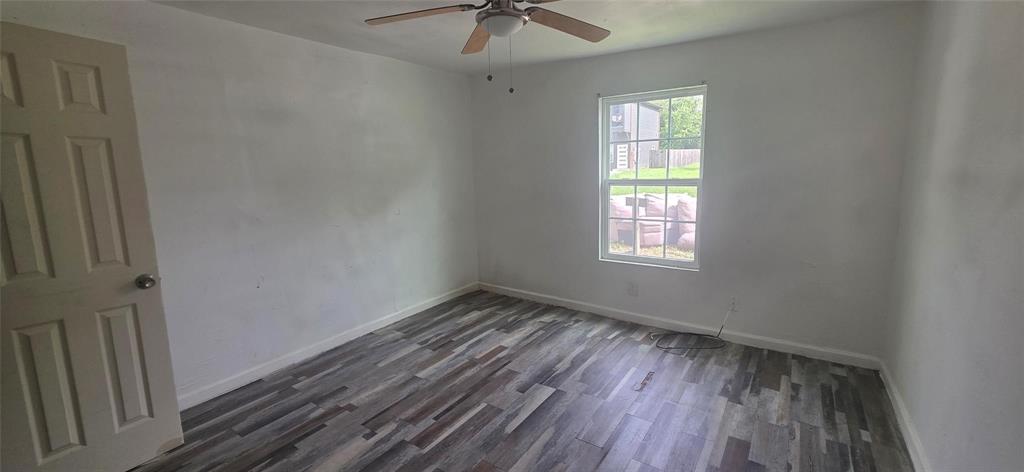 Room featuring wood-finish flooring, a multi-pane window, and a ceiling fan