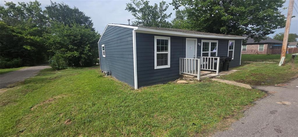 Exterior featuring dark blue horizontal siding, white trim, multiple grid-pane windows, and a raised wooden porch with white railing