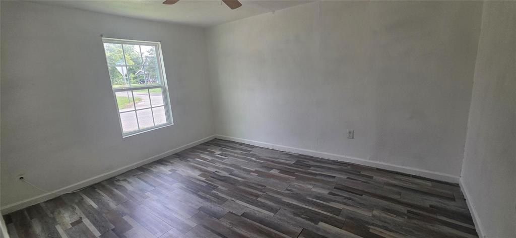 Room featuring wood-finish flooring, a multi-pane window, and a ceiling fan