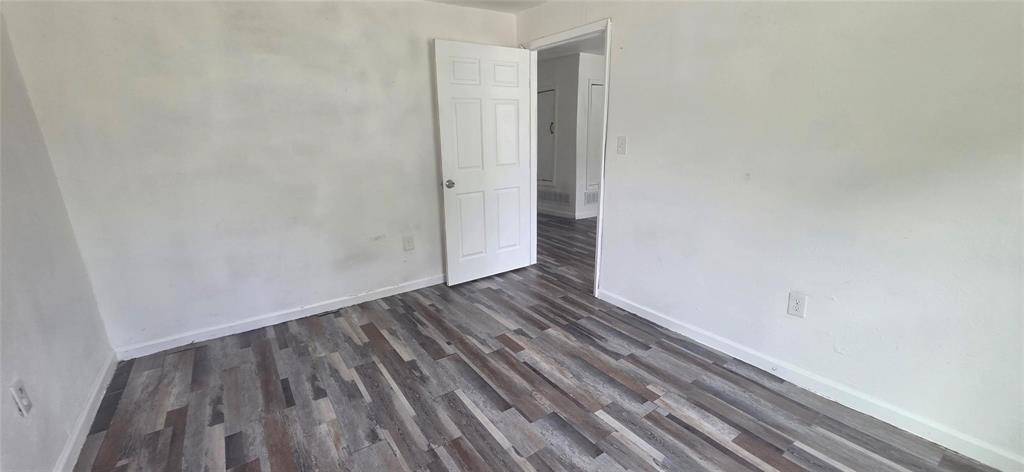 Interior room featuring wood-finish flooring and a six-panel door