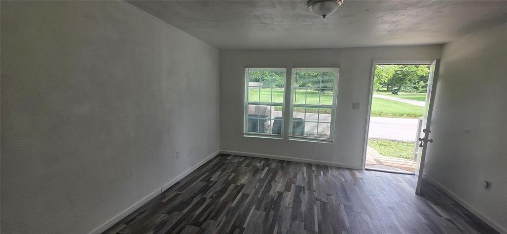 Interior space featuring wood-finish flooring, dual-pane windows with grid detailing, and a flush-mount ceiling light fixture