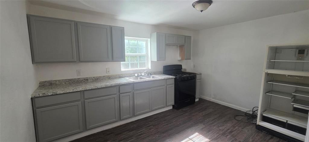 Kitchen featuring grey cabinetry, stone-finish countertops, wood-finish flooring, dual-basin sink, and dark-finish appliances