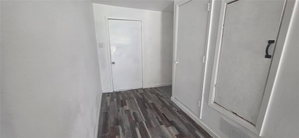 Interior space featuring wood-finish flooring, two sets of built-in wall cabinetry with recessed panels, and a single-panel interior door