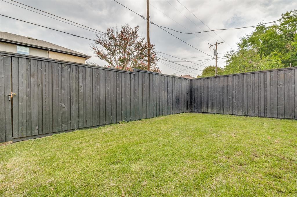 Rear yard featuring a tall, dark-stained wood privacy fence and a gated entry