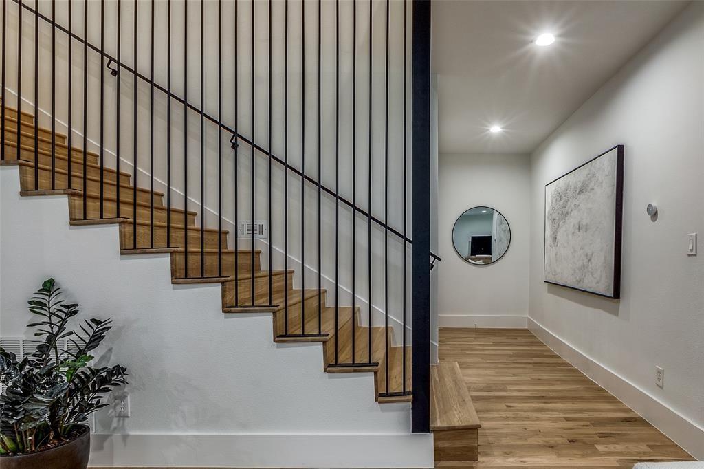 Staircase featuring wood-finish treads, vertical black metal balusters, integrated recessed lighting, and wood-finish flooring