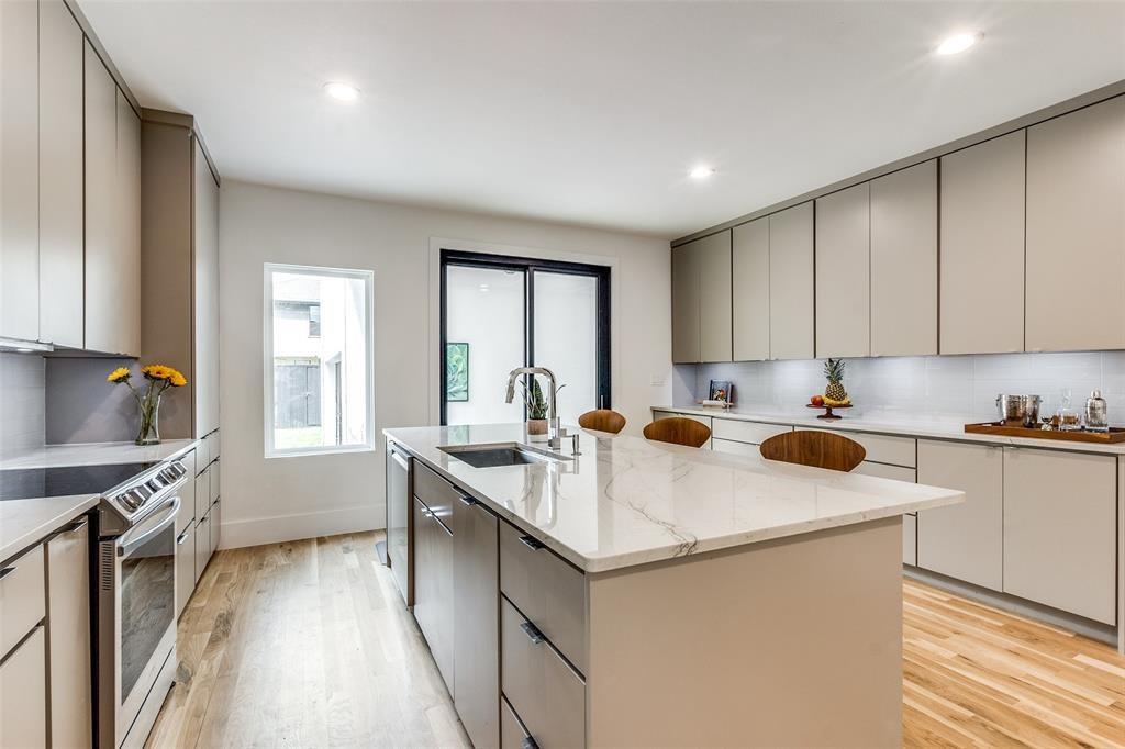 Kitchen featuring floor-to-ceiling cabinetry, a central island with a stone-finish countertop, stainless steel appliances, recessed lighting, and wood-finish flooring