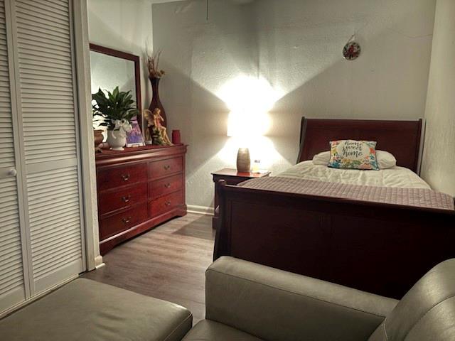 Wood-finish flooring and floor-to-ceiling closet featuring dual louvered doors and ceiling fan