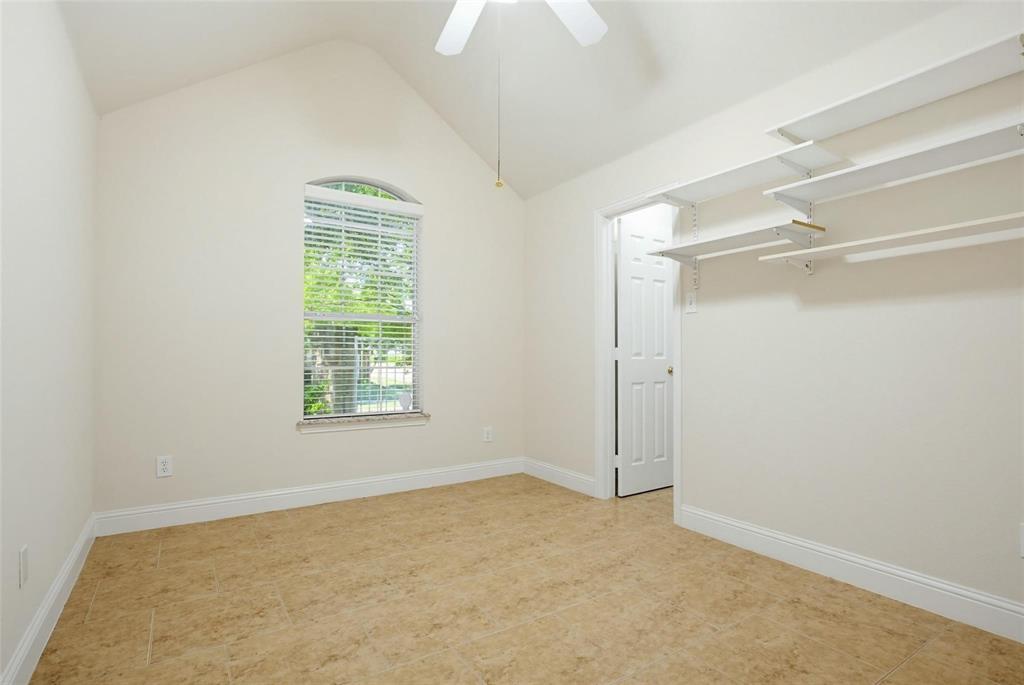 Vaulted ceiling, arched window, tile flooring, and wall-mounted shelving units Vaulted ceiling, arched window, tile flooring, and wall-mounted shelving units