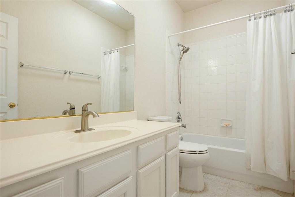 Bathroom featuring a vanity with an integrated countertop, large wall-mounted mirror, brushed nickel faucet, and a shower-tub combination with white tile surround Bathroom featuring a vanity with an integrated countertop, large wall-mounted mirror, brushed nickel faucet, and a shower-tub combination with white tile surround