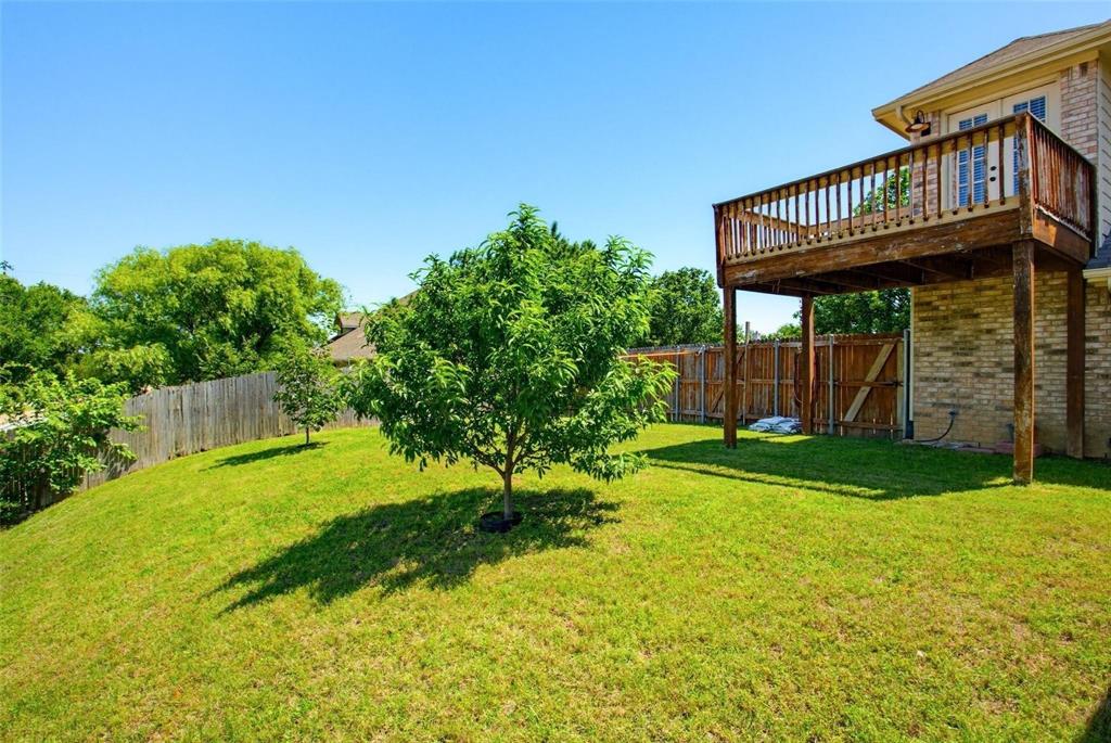 Backyard featuring a grass lawn, wood-framed elevated deck, brick exterior siding, and perimeter wood fencing