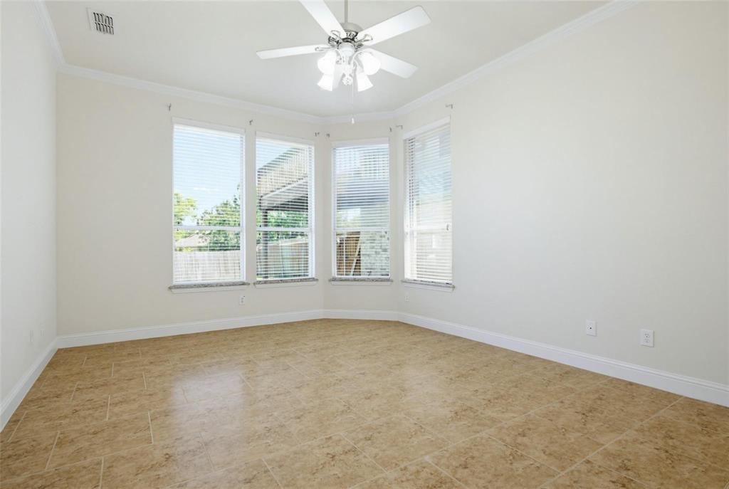 Bay window featuring four expansive windows, neutral tile flooring, white crown molding, and a central ceiling fan with integrated lighting