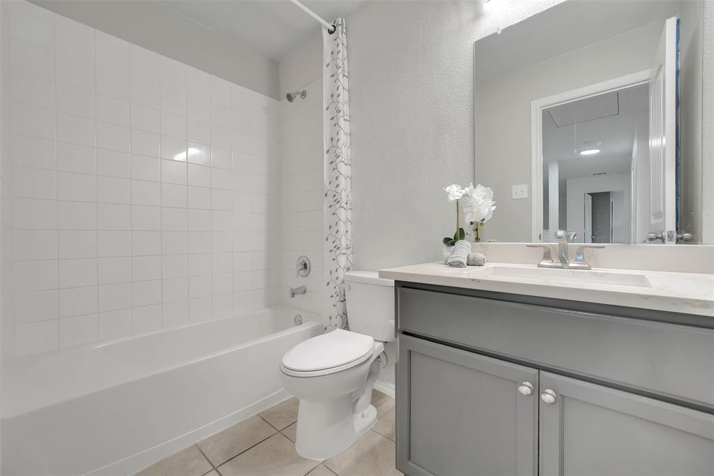 Full bathroom with vanity, tile patterned floors, toilet, and shower / tub combo with curtain