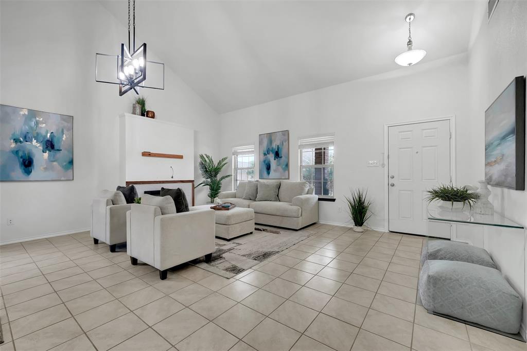 Living area featuring light tile patterned floors, baseboards, high vaulted ceiling, and an inviting chandelier